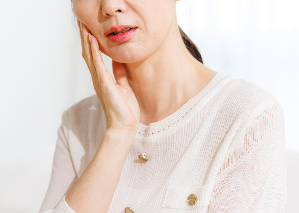볼을 짚으며 턱 통증을 호소하는 모습