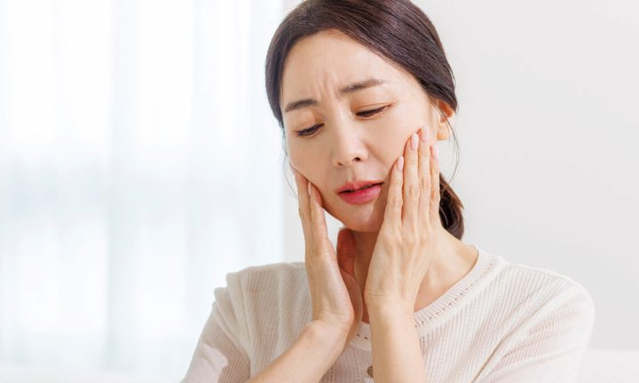 입 벌릴 때 턱 통증으로 양손으로 볼을 감싼 모습