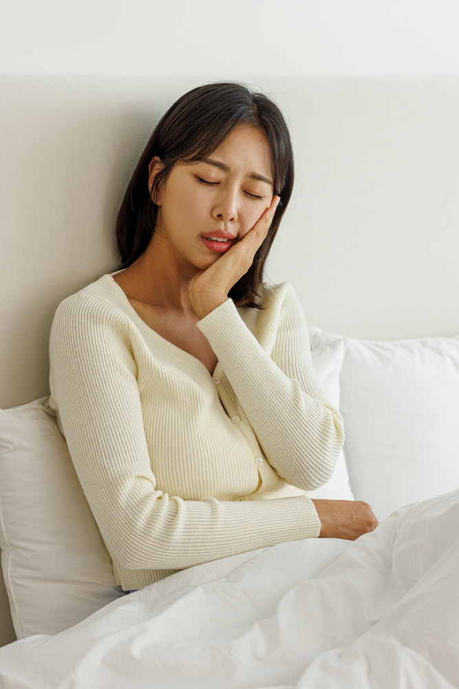 밤에 침대에서 볼과 턱을 감싸고 있는 여성