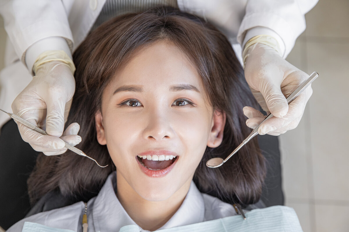 치경과 탐침으로 환자의 입안을 살펴보는 치과 검진 장면